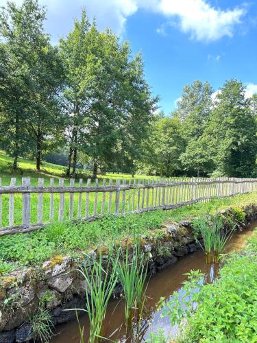 a wooden fence next to a stream in a garden at Lac privé, forêt, calme absolu dans un gîte tout confort in Saint-Estèphe