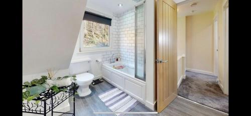 a bathroom with a tub and a toilet and a window at Ormasaig, Self Catering, One Mile to Town & close to Ben Nevis in Fort William