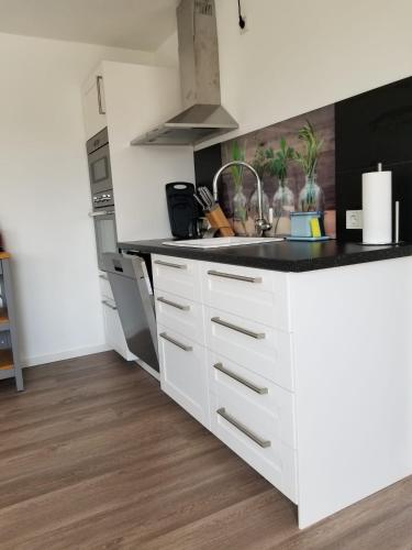 a kitchen with white cabinets and a black counter top at Ferienwohnung Wiehl Sonnenterrasse in Wiehl