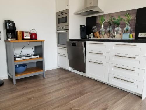 uma cozinha com armários brancos e electrodomésticos de aço inoxidável em Ferienwohnung Wiehl Sonnenterrasse em Wiehl