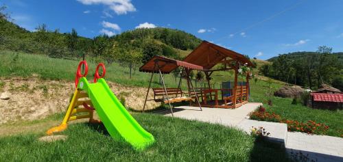 a playground with a green slide and a swing at Pensiunea Apuseni in Vidra