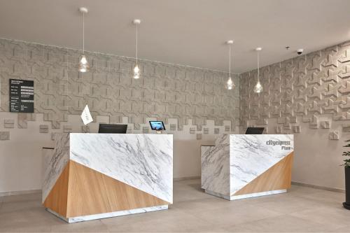 a lobby with two reception desks with marble walls at City Express Plus by Marriott Cancun Aeropuerto Riviera in Cancún