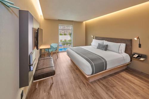 a bedroom with a large bed and a television at City Express Plus by Marriott Cancun Aeropuerto Riviera in Cancún
