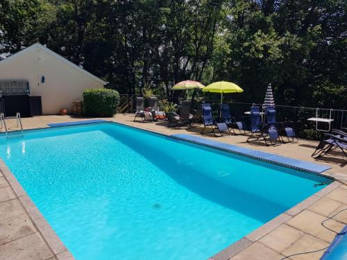 a large blue swimming pool with chairs and umbrellas at Woodside Ash hot tub & pool (sleeps 4-6) in Bideford