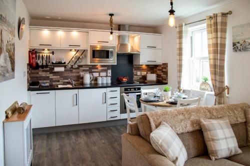 a kitchen and living room with a couch and a table at Sandy Bottom in Filey