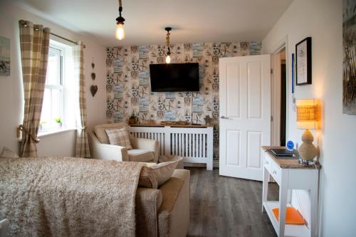 a living room with a couch and a tv on a wall at Sandy Bottom in Filey