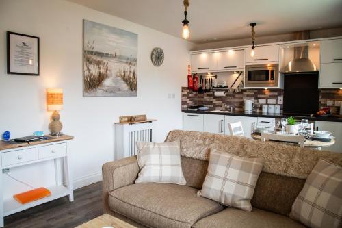 a living room with a couch and a kitchen at Sandy Bottom in Filey
