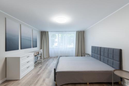 a bedroom with a bed and a desk and a window at Stiklo Apartamentai in Radviliškis