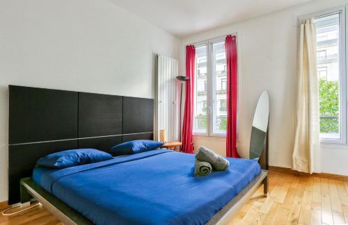 Schlafzimmer mit einem Bett mit blauer Bettwäsche und einem Surfbrett in der Unterkunft Appartement Quartier Champs-Élysées 4 in Paris