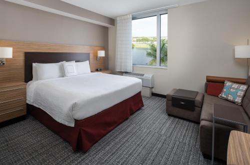 TownePlace Suites Miami Kendall West في كيندال: غرفة فندقية بسرير كبير واريكة