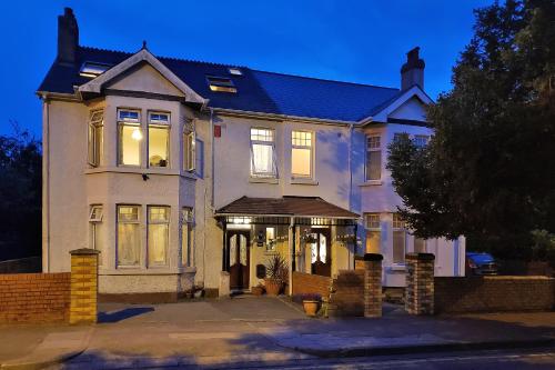 a large white house with its lights on at Weaver's House B and B in Cardiff