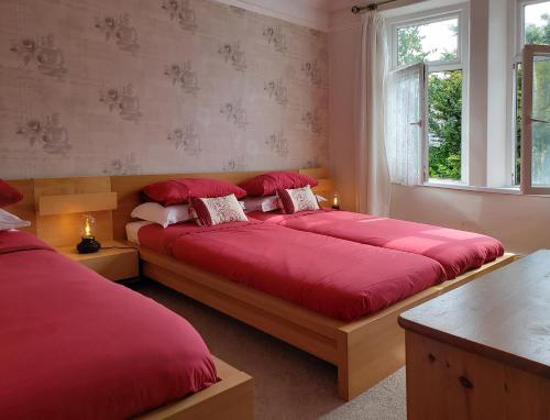 um quarto com duas camas com capas vermelhas em Weaver's House B and B em Cardiff
