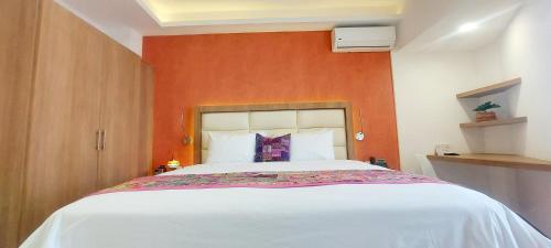 1 dormitorio con 1 cama blanca grande y pared de color naranja en Hotel Boutique Dawat WTC, en Ciudad de México