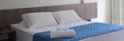 a bed with a blue blanket and white pillows at Monza Palace Hotel in Natal