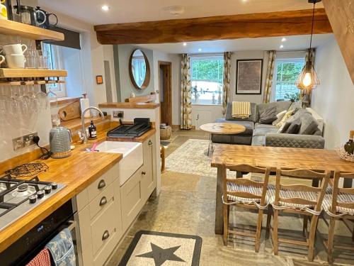 a kitchen and living room with a couch and a table at Weavers Cottage, Tideswell, sleeps 6, dog friendly in Buxton