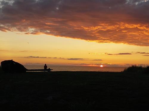 uma pessoa sentada num banco a ver o pôr-do-sol em Treimani Meremaja em Treimani