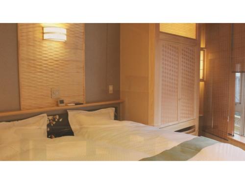 黒部市にあるUnazuki Onsen Sanyanagitei - Vacation STAY 06451vの白いシーツと窓のあるベッドのある寝室