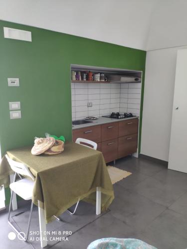 um quarto com uma mesa e uma cozinha com paredes verdes em Taverna Garibaldi Casa Lucia em Minervino Murge