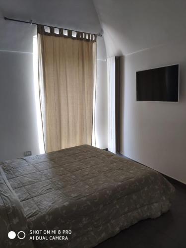 1 dormitorio con 1 cama, TV y ventana en Taverna Garibaldi Casa Lucia, en Minervino Murge