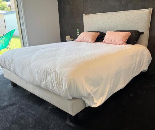 een groot bed met twee roze kussens erop bij La Villa Cosy in Espalion