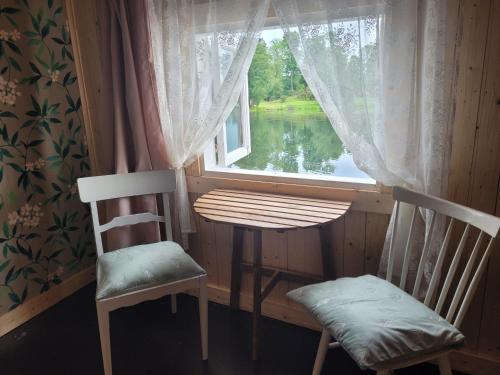 a table and two chairs in a room with a window at Laivu māja uz Alūksnes ezera/ Boat house on a Lake in Alūksne