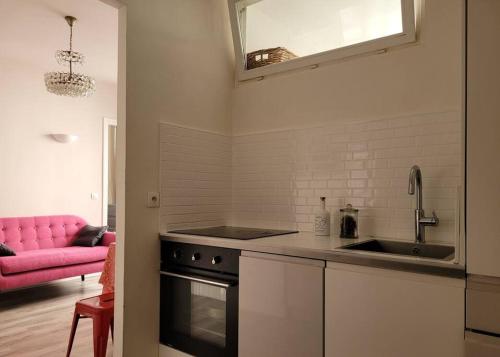 een keuken met een wastafel en een roze bank bij Appartement entier - Paris 12 in Parijs