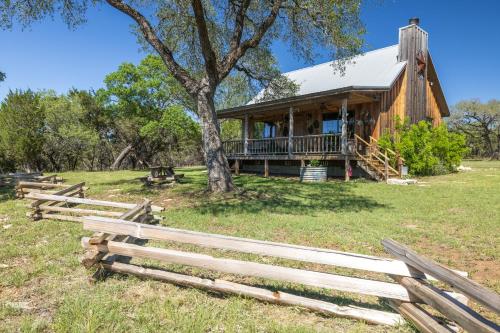 a log cabin with a fence in front of it at Inn at Sunset Mill Ranch in Wimberley