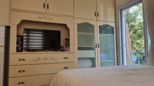 a bedroom with a bed and a dresser with a television at Lovely studio with balcony in Rechovot