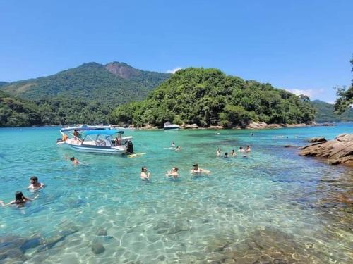 a group of people in the water with a boat at Encanto do Beija-flor in Angra dos Reis