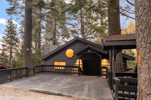 a black cabin in the woods with a tree at Modern Treetop Cabin by Lake Arrowhead Village in Lake Arrowhead