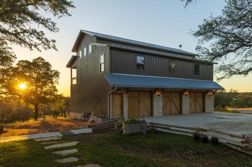 a house with a gambrel roof with the sun setting at Inn at Sunset Mill Ranch in Wimberley
