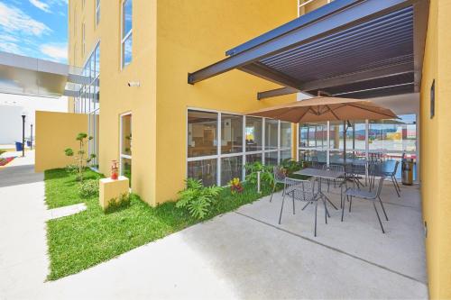 a patio with a table and chairs and an umbrella at City Express by Marriott Comitán in Comitán de Domínguez