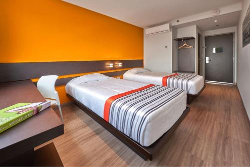 two beds in a room with an orange wall at City Express Junior by Marriott Leon Centro de Convenciones in León