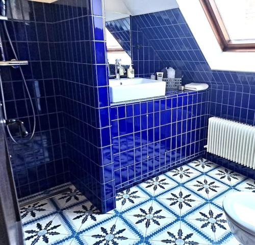 baño de azulejos azules con bañera y lavamanos en Maison Marcks Champagne, en Ay