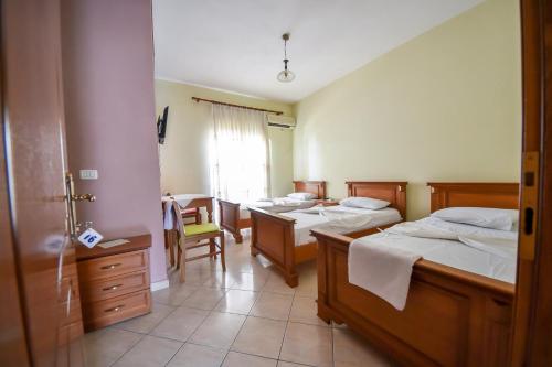 um quarto com três camas e uma mesa e cadeiras em Hotel Geraldo em Gjirokastër