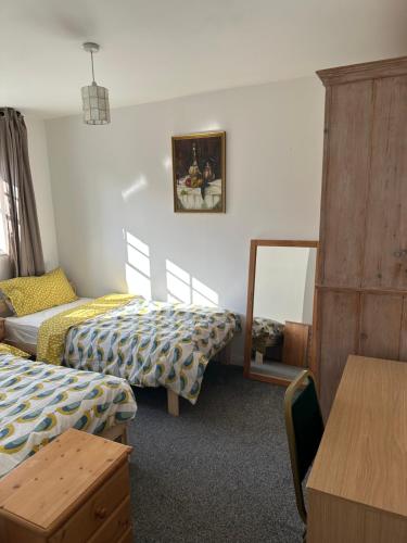 una camera con due letti e uno specchio di Chessington Home Stay , 3 Bed 6 Guests Free Parking Near M25 JCT9, Chessington world of Adv Resort, Kingston, Epsom, Great for Families & Groups a Chessington