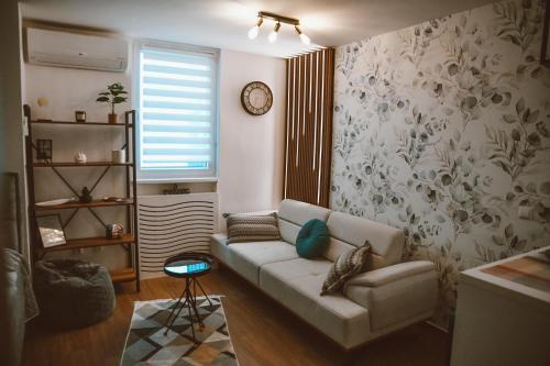 a living room with a couch and a clock on the wall at Studio apartman NEI in Tuzla