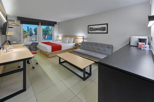 a hotel room with a bed and a couch at City Express by Marriott Los Mochis in Los Mochis