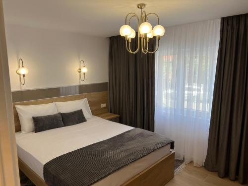 a bedroom with a large bed and a chandelier at Luxury Apartment Centrul Vechi in Curtea de Argeş