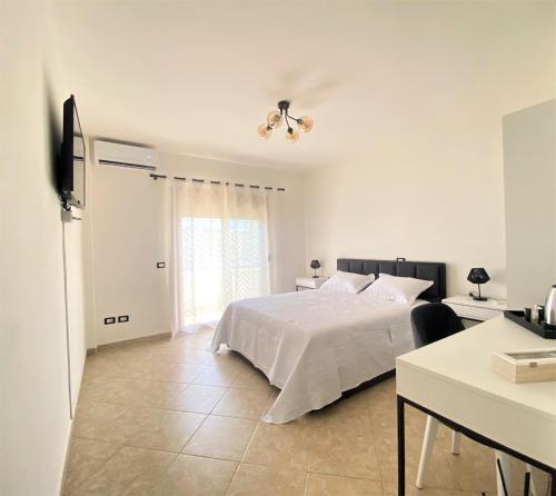 都拉斯The White Corner的一间带床和桌子的白色卧室