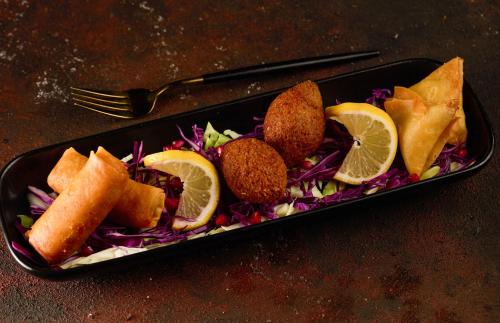 a black plate of food with cabbage and lemon slices at فندق سنبات بلاتينيوم in Jazan