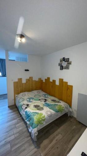 Schlafzimmer mit einem Bett mit einem Kopfteil aus Holz in der Unterkunft Logement 2 personnes. in Vitry-le-François