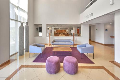sala de estar con sillas de color púrpura y mesa en City Express by Marriott Celaya Parque en Celaya