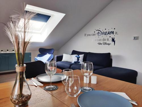 una mesa con copas de vino y un sofá azul en Akela - Appartement à 12mn de Disneyland Paris !, en Bussy-Saint-Georges