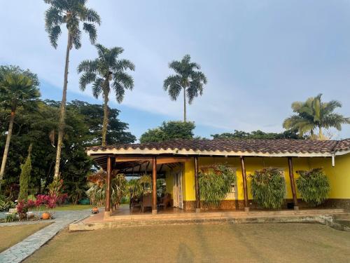 a yellow house with palm trees in the background at Finca El Cortijo Pereira in Pereira