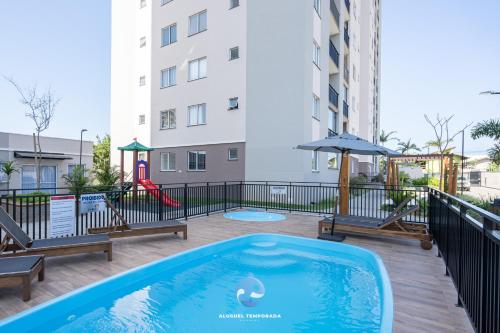 a swimming pool with a playground in a building at Apto a 150m DA PRAIA e 15min BETO CARREIRO com WI-FI, PISCINA, PORTARIA 24h, PLAYGROUND INFANTIL, QUADRA DE ESPORTES sacada com CHURRASQUEIRA e vaga de GARAGEM in Piçarras