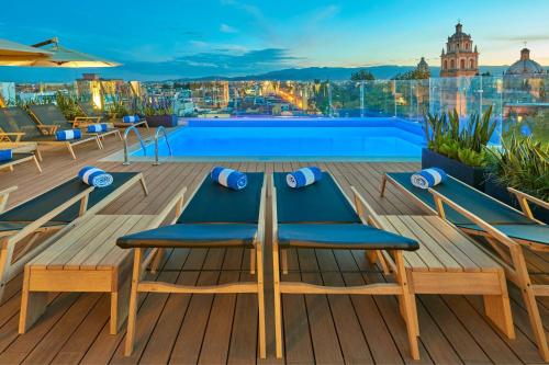 a deck with a table and chairs and a swimming pool at City Centro by Marriott San Luis Potosi in San Luis Potosí