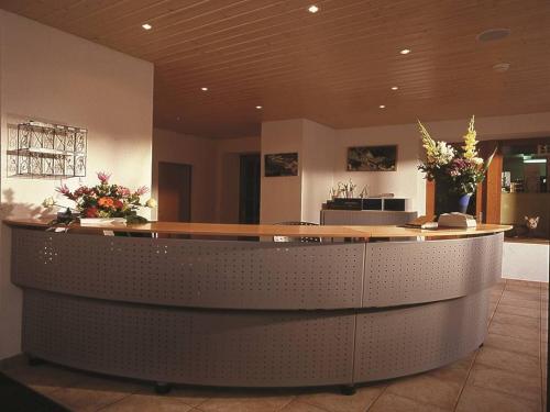 a lobby with a counter with flowers on it at Hotel du Pigne in Arolla