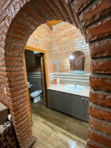 a bathroom with a brick wall and a sink at Vila Mario Berat in Berat