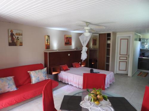 a living room with a bed and a red couch at Vacances Antilles in La Trinité